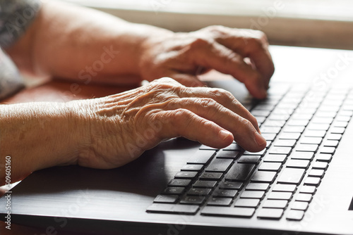 Close-up of an old woman's hand using a laptop