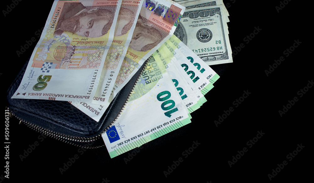 one hundred American dollars and one hundred euros a lot from a black wallet, the Bulgarian lev lies on top of the wallet on a black background one hundred American dollars and one hundred euros a lot from a black wallet, the Bulgarian lev lies on top of the wallet on a black background