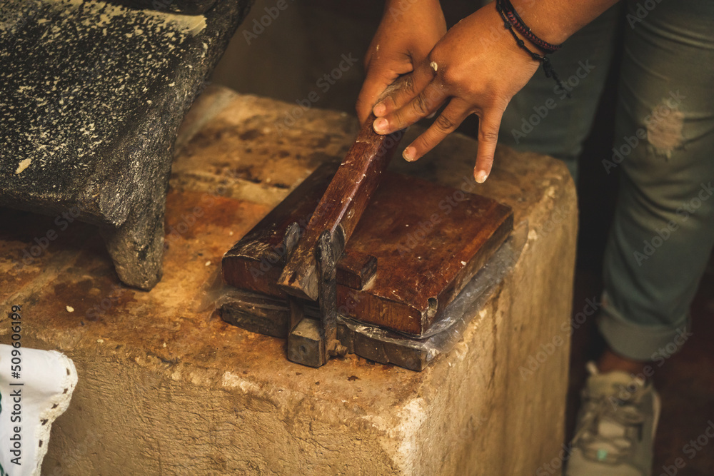 Mujer mexicana torteando maza de maíz en un metate y una estufa de leña para hacer tortillas caseras Mujer mexicana torteando maza de maíz en un metate y una estufa de leña para hacer tortillas caseras