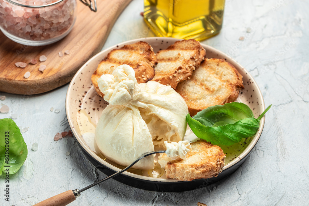Italian burrata cheese, white balls of burrata or burratina cheese Basil and Olive Oil and Ciabatta. place for text, top view Italian burrata cheese, white balls of burrata or burratina cheese Basil and Olive Oil and Ciabatta. place for text, top view