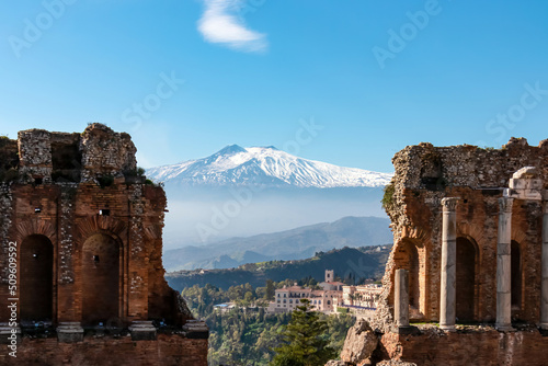 Panoramic view of snow capped Mount Etna volcano on a sunny day seen from the ancient Greek theater of Taormina, island Sicily, Italy, Europe, EU. Travel destination at the Mediterranean sea. Tourism