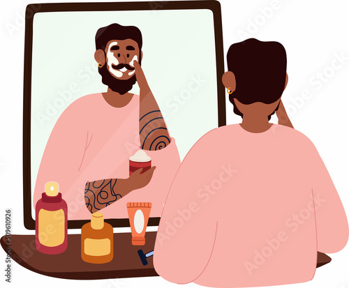 A black man stands in front of a mirror and makes a face mask. A man takes care of his appearance.