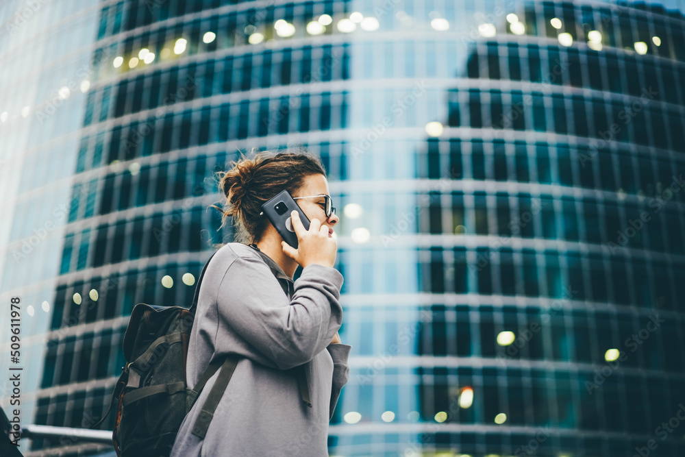 Young woman holds smartphone and standing against big modern financial centers in evening Young woman holds smartphone and standing against big modern financial centers in evening