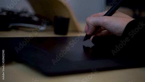 Close-up of hand drawing on a digital tablet with pen. Professional retoucher working on graphic tablet.
