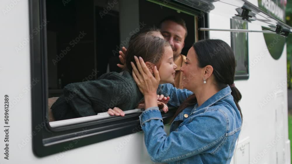Happy young mother kissing ker kids to say goodbye before caravan trip with their father.