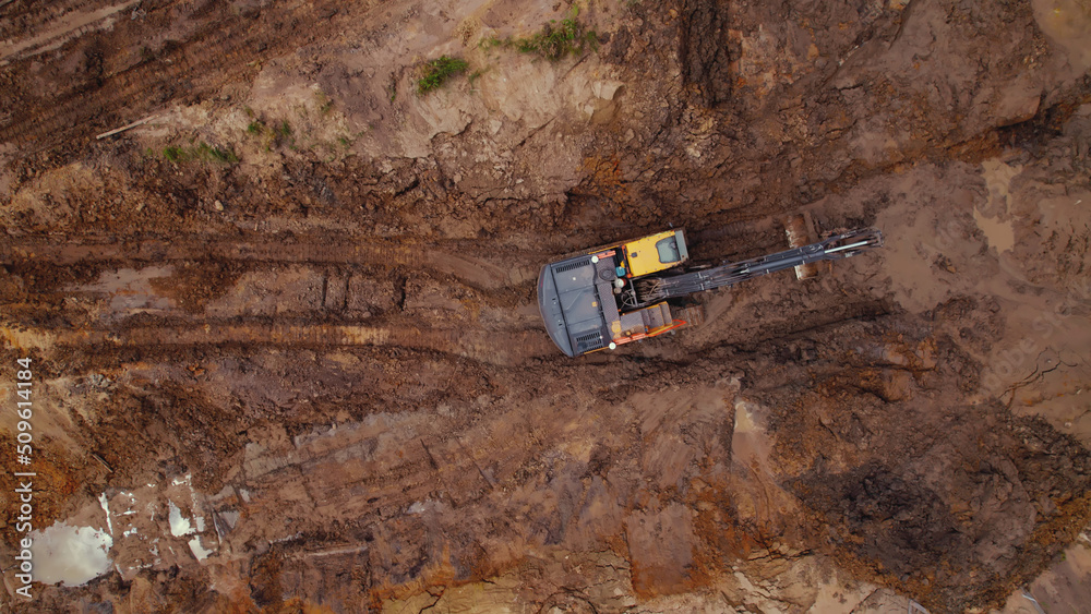 Aerial view of an excavator digging up the road on a construction site - copy space. High quality photo