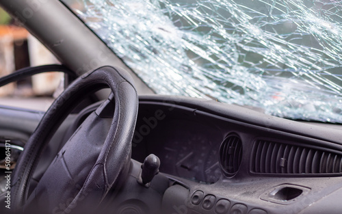 Close-up of the steering wheel of a car after an accident. The driver's airbags did not deploy. Soft focus. Broken windshield with steering wheel. Vehicle interior. Black dashboard and steering wheel.