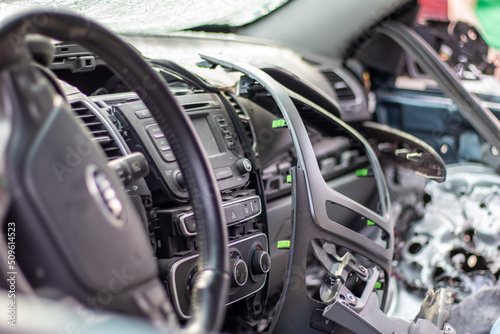 Close-up of the steering wheel of a car after an accident. The driver's airbags did not deploy. Soft focus. Broken windshield with steering wheel. Vehicle interior. Black dashboard and steering wheel. © Yevhen Roshchyn