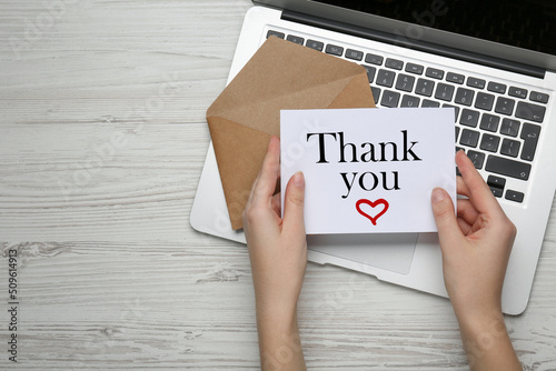 Принти на полотні Woman holding card with phrase Thank You ar white wooden table, top view