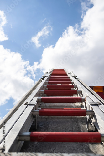 Retractable ladder on a fire engine, against the background of a blue sky and clouds. Bottom view. 