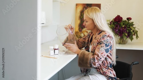 Young female painter painter on glassware sitting in wheelchair photo