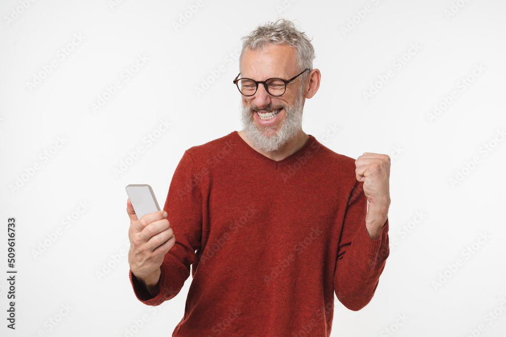 Grey-haired mature man celebrating victory win online casino bet on sport, winning money on cellphone smart phone isolated in white background. Sale offer discount Grey-haired mature man celebrating victory win online casino bet on sport, winning money on cellphone smart phone isolated in white background. Sale offer discount