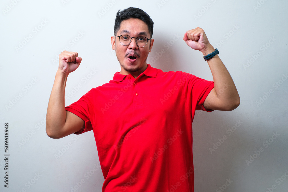 Young handsome man wearing casual shirt and glasses very happy and excited doing winner gesture with arms raised, smiling and screaming for success. Celebration concept Young handsome man wearing casual shirt and glasses very happy and excited doing winner gesture with arms raised, smiling and screaming for success. Celebration concept