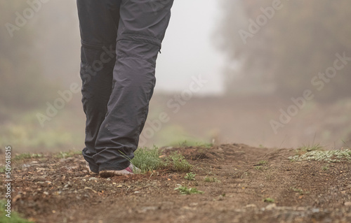 Selective focus shot of footsteps of person walking in nature in foggy weather.