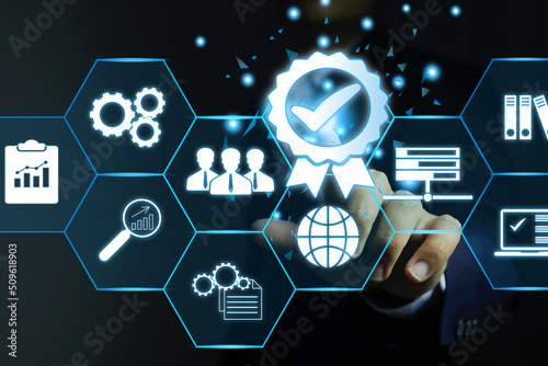 The hand of a businessman or an auditor click on the quality mark of a product or a warrant of quality produced by an industrial plant. Production process assessment under ISO 9001 compliance concept.