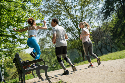 A group of people exercise and run at the park. 