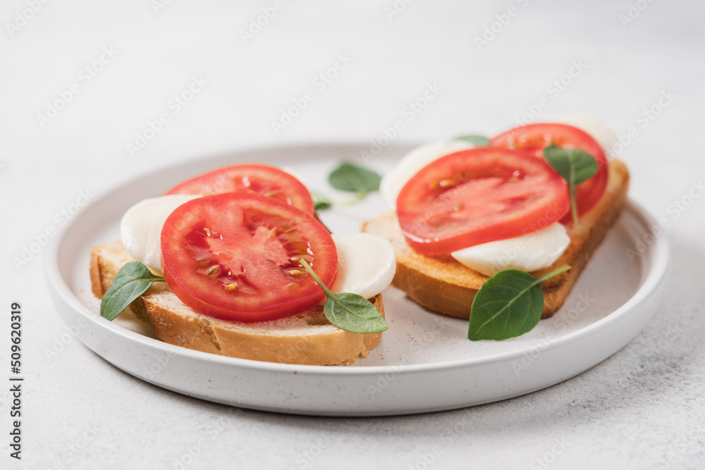 Bruschetta with mozzarella, tomatoes and basil on plate, close-up view Bruschetta with mozzarella, tomatoes and basil on plate, close-up view