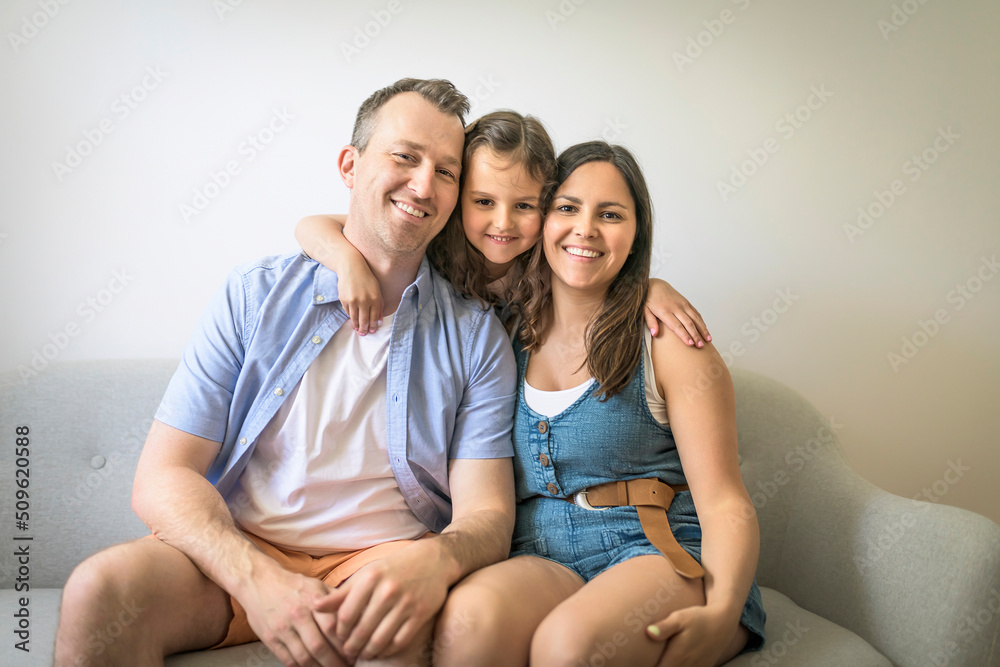 Cheerful people sitting on couch in living room have fun with his daughter
