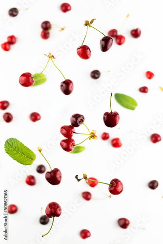 Blurred image of falling ripe cherries on a white background.