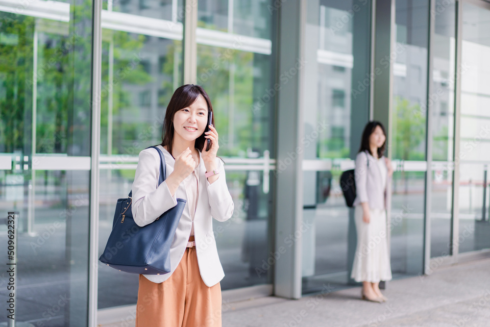 電話でタクシーを呼ぶ若いビジネスウーマン 電話でタクシーを呼ぶ若いビジネスウーマン
