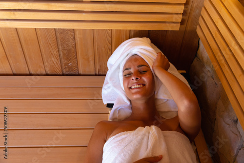 Caucasian young woman in a bathrobe relaxing in the sauna
