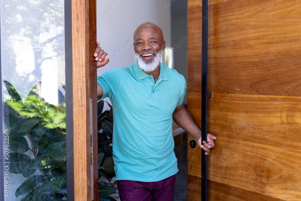 Portrait of cheerful african american senior man welcoming while standing at doorway in nursing home Portrait of cheerful african american senior man welcoming while standing at doorway in nursing home