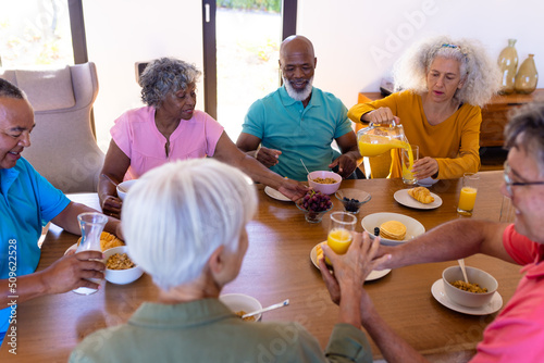 High angle view of multiracial senior friends having breakfast on dining table in retirement home
