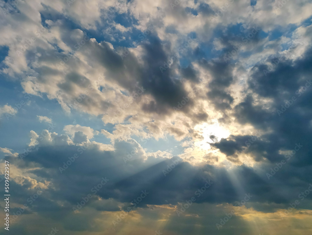 Obraz premium Dramatic stormy sunset sky with sun rays breaking through gloomy clouds.