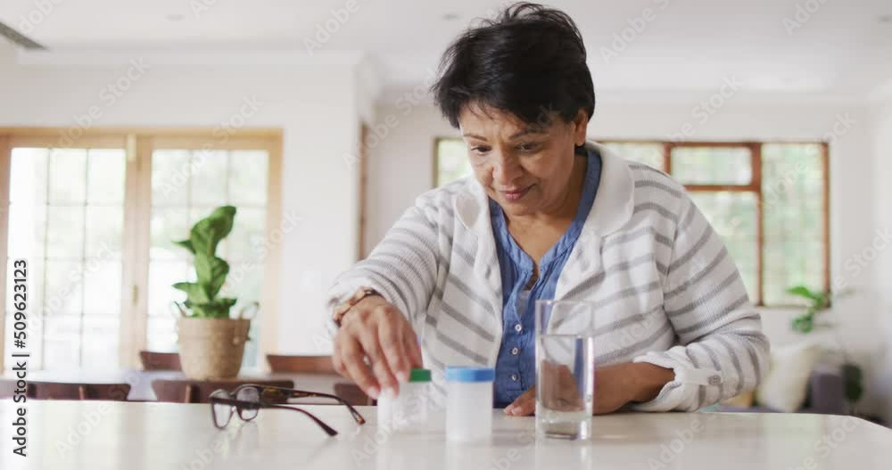 Asian senior woman checking her medicine containers in the living room at home Asian senior woman checking her medicine containers in the living room at home