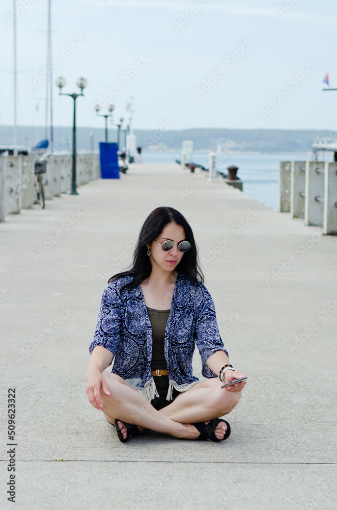 Fototapeta premium Portrait of young happy brunette woman in sunglasses relaxing at the seaside, beach at Adriatic sea. Summer vacation. Travel. Trip