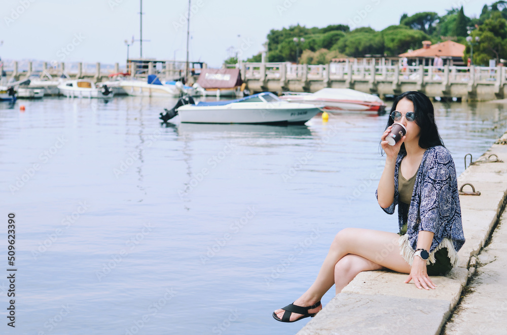 Lifestyle Portrait. Beautiful happy woman walking, relaxing, enjoying in sunny day at beach. Summer. Drinking coffee. Adriatic Sea