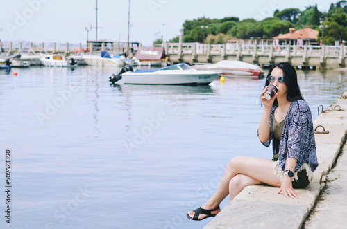 Lifestyle Portrait. Beautiful happy woman walking, relaxing, enjoying in sunny day at beach. Summer. Drinking coffee. Adriatic Sea © Oleksandra