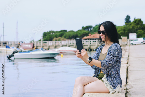 Portrait of young happy business woman relaxing, working at beach at Adriatic seaside. Using laptop. Technology. Video call. Summer vacation.  © Oleksandra