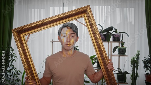 Wallpaper Mural A young Asian man with unusual make-up and a large golden frame posing for the camera. Torontodigital.ca