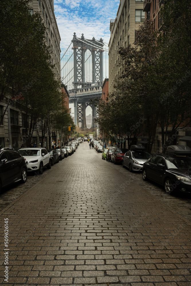 Manhattan bridge seen from Washington St alley enclosed by two brick buildings.