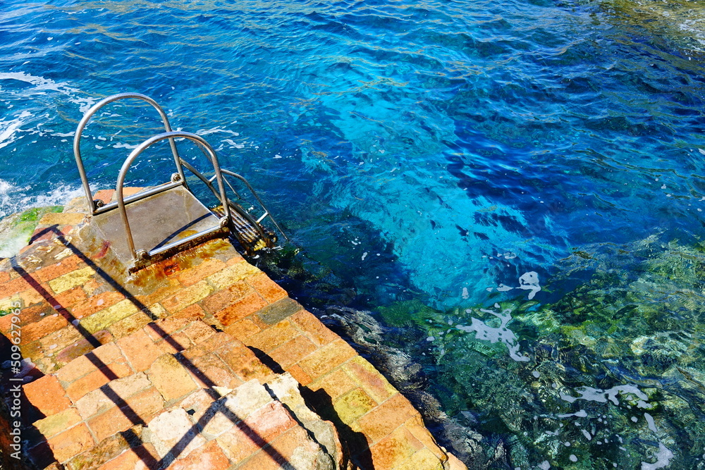 Metal stairs to the clear waters of the Tyrrhenian sea in Capri island, Italy