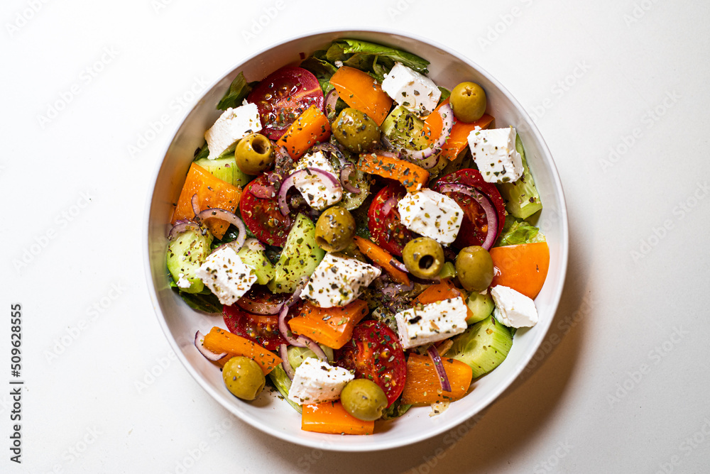 Fresh sliced vegetables for salad in a plate on a white background Fresh sliced vegetables for salad in a plate on a white background