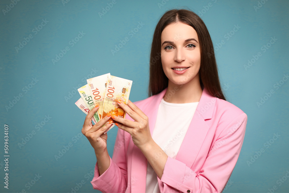 Young woman holding israel shekels looking positive and happy standing and smiling with a confident smile Young woman holding israel shekels looking positive and happy standing and smiling with a confident smile