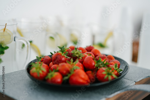 Fresh Strawberry closeup on black plate and stone table blur background