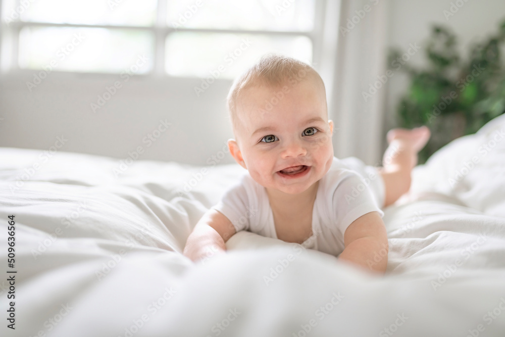 Adorable baby boy in white sunny bedroom in the morning at home Adorable baby boy in white sunny bedroom in the morning at home