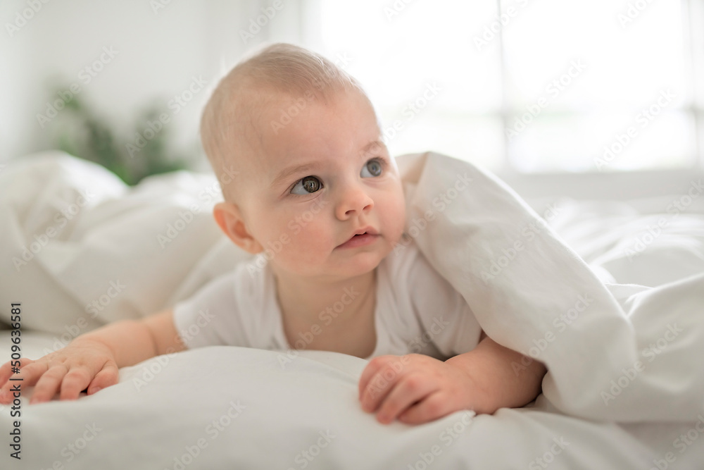 Adorable baby boy in white sunny bedroom in the morning at home Adorable baby boy in white sunny bedroom in the morning at home