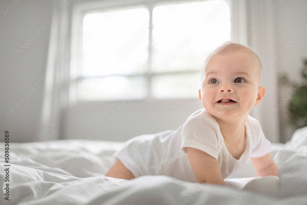 Adorable baby boy in white sunny bedroom in the morning at home Adorable baby boy in white sunny bedroom in the morning at home