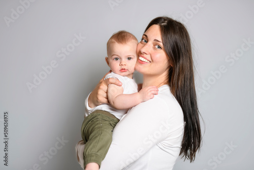 Cheerful baby boy toddler with his mother on white studio background