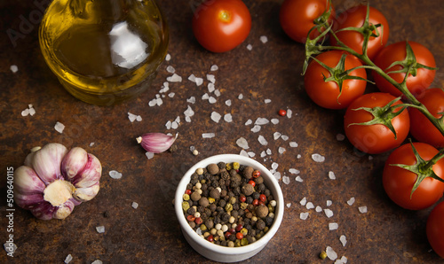 Fragrant spices are scattered on the table. Next to a sprig of cherry tomatoes and olive oil.