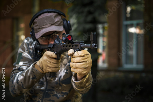 Private military contractor at tactical training course. Shooter with a gun in military uniform. Police training in shooting gallery with weapon. Shotgun weapon action course. Outdoor shooting range