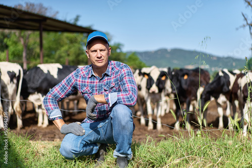 portrait of a farmer resting on green grass among cows