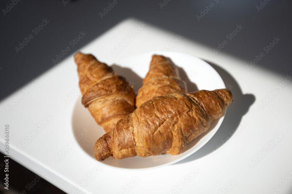 three appetizing rich fresh croissants on a white plate