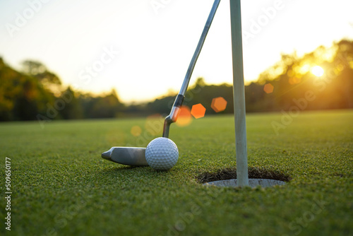 Golf clubs and ball on a green lawn in a beautiful golf course with morning sunshine.