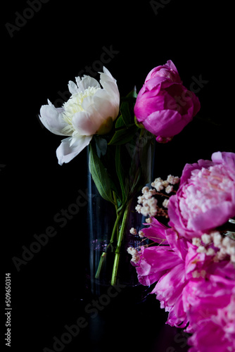 wine and flowers. still life with flowers. Bouquet of white and pink peony on a black background. Flower in a glass of water. 