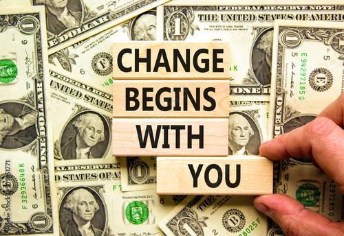 Change begins with you symbol. Concept words Change begins with you on wooden blocks on beautiful background from dollar bills. Businessman hand. Business motivational change begins with you concept.
